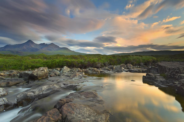 Isle of Skye, Scotland, Europe. The last sunset colors reflected in the water. In the background the peaks of the Black Cuillin.