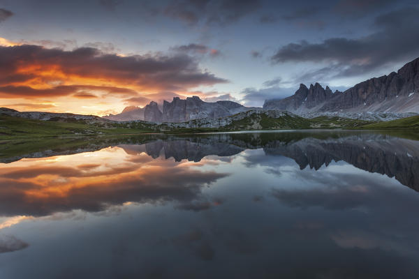 Dolomites, Italy. Clouds and colors at dawn are reflected at Laghi dei Piani, not far from Locatelli hut in Sesto Dolomites.