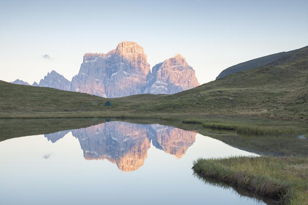 A little alpine lake reflecting The Dolomites peaks at Sunset, Italy