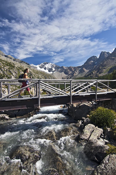 A Hiker crosses a bridge over the Alpine river in the beautiful Masino Valley, Valtellina, Lombardy, Italy