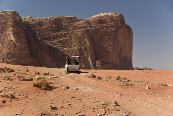 A jeep of tourists during a hike on the sands of Wadi Rum desert, where there are ancient mountains of granite rock, Jordan
