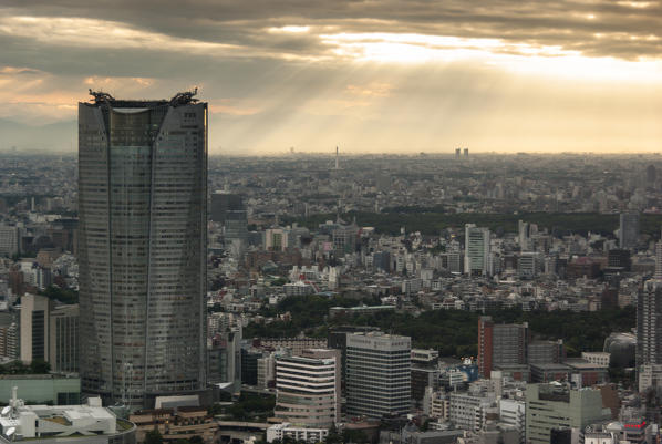 the rays of the sun filtering through the clouds over the city of tokyo