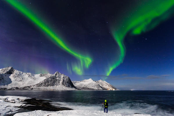 Photographer taking pictures of northern Lights (Aurora Borealis) at djevelens tanngard, senja, nordland, norway, europe