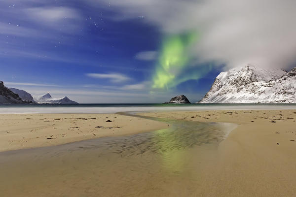 Northern lights (aurora borealis) reflecting into a small water stream at Haukland Beach, Leknes, lofoten islands, nordland, norway, europe