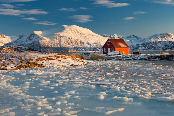 Red house on the shore of the fiord in Sommaroy, troms, tromso, norvegia, europe