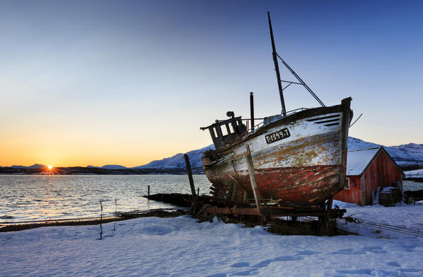 Shipwreck on the shore of Tromso fiord at sunrise, troms, norway, europe