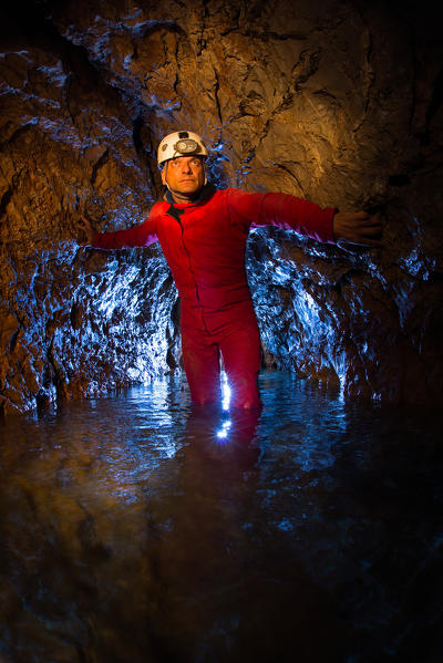 A spelunker enters a cave with water 
