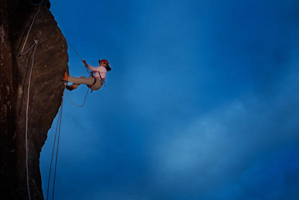 Rock climber at work with a blue cloudy sky as background 