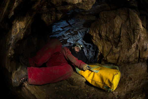 A speleologist in a cave with his bag