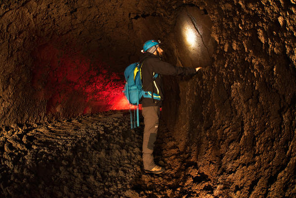 Etna volcano, Catania, Sicily, Italy. Man exploring an underground lava cave of the Etna volcano