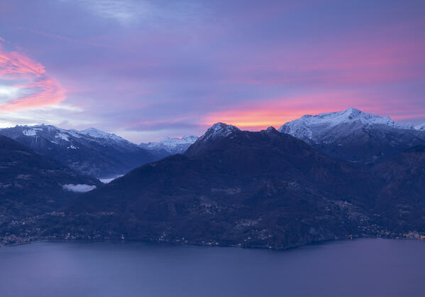 Burning sky at dawn over the snowcapped mountains of valsassina, view from  Plesio,Lake Como, Lombardy, Italy