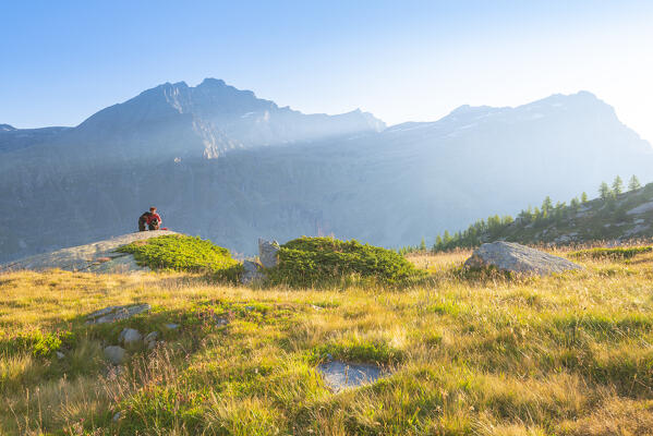An hiker admires the sunset near Refuge Jervis, Valle dell Orco, Gran Paradiso National Park, Province of Turin, Piedmont, Italian alps, Italy