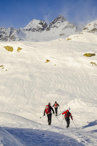 Hikers in the snow, in the presence of the peaks Monveso and Roccia Azzurra (Soana valley, Gran paradiso National Park, Piedmont)