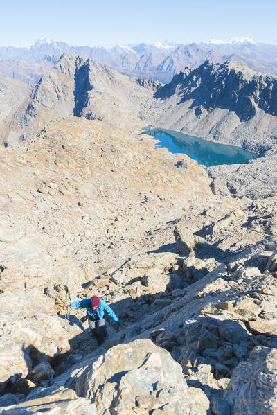 Alpinist climbing Mont Colmet, with the view of Pietra Rossa lake, Arpy Valley, Valdigne, Aosta Valley, Italian alps, Italy