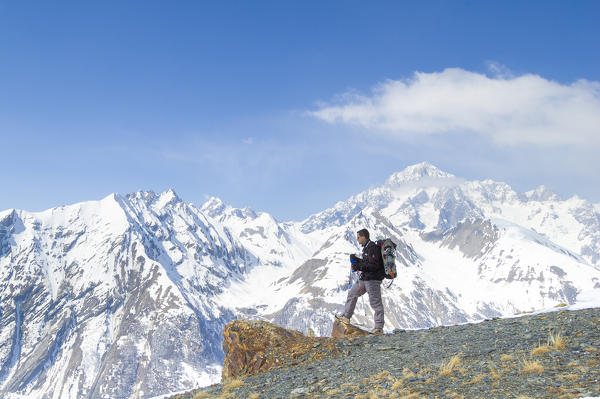 Alpinist on the summit with Mont Blanc in the background, Valdigne, Aosta Valley, Italian alps, Italy