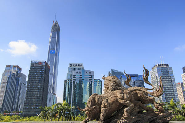 Stock market building in Shenzhen, one of the three stock markets in China, with the copper bull statue on foreground. On background the tallest building of Shenzhen: the Ping An IFC, China