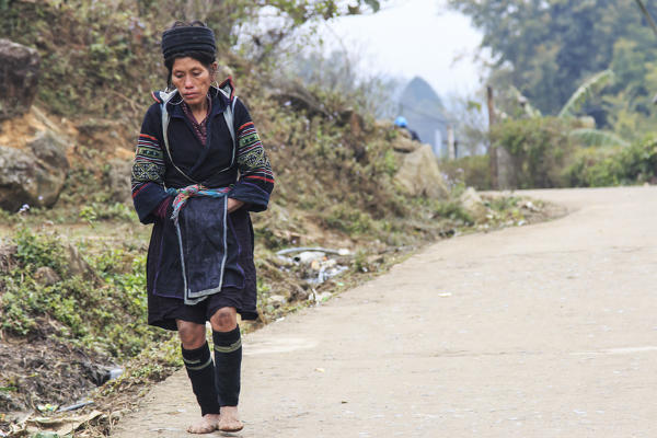 Aboriginal woman of the mountains of Sapa, in north Vietnam, dressed with the traditional attire walking to her village
