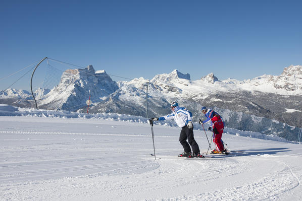 Skiers on the ski slope of Mount Faloria with the snowy peaks in the background Cortina D'Ampezzo Dolomites Veneto Italy Europe