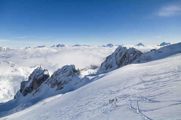 The alpine skiers proceed in the snowy valley toward the high peaks of the Marmolada Dolomites Veneto italy Europe