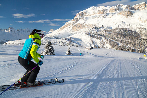 Blue sky and sun frame the skier on the snowy ski slopes of Cherz Arabba Dolomites Veneto Italy Europe