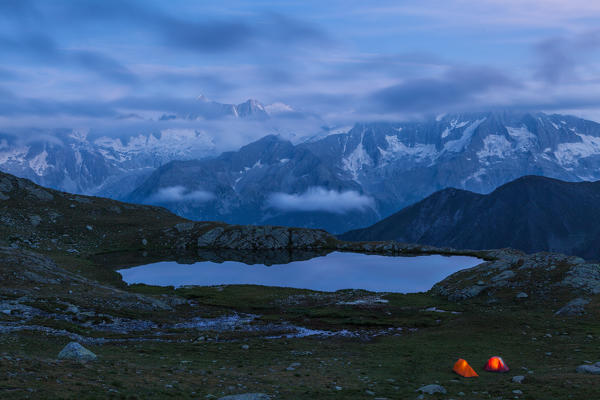 Strino lakes, Stelvio National park, Trento province, Trentino Alto Adige, Italy. Two tents and the Presanella's range at twilight.