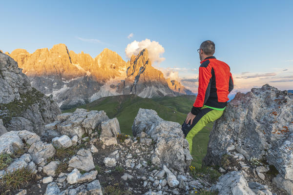 hiker admires the sunset on the walls of the Pale di San Martino (Pala group) seen from the Castellazzo mountain, Rolle pass, Trentino, Trento, Italy