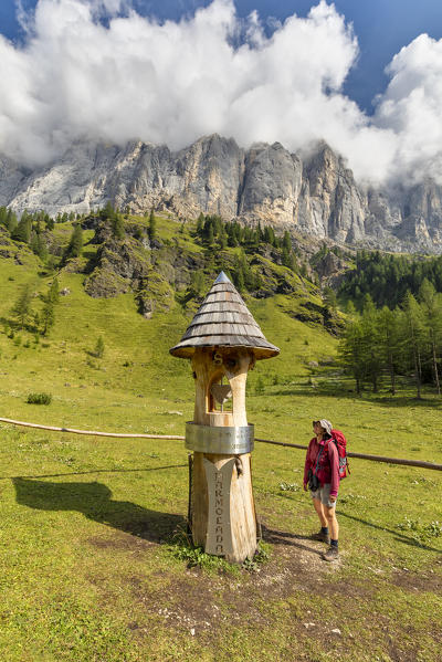 hiker near the totem representing the geographical center of the Dolomites, in the Ombretta valley at the foot of the Marmolada, Rocca Pietore, Belluno, Veneto, Italy