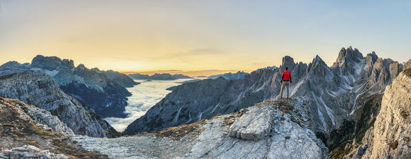 Hiker admiring the Dolomites at sunrise in front of Cadini di Misurina, Auronzo di Cadore, Belluno, Veneto, Italy (MR)