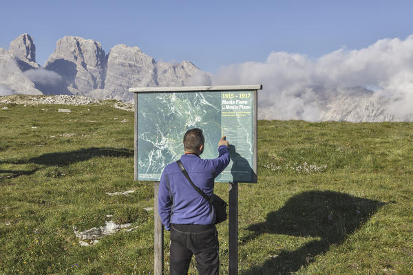 Tourist is consulting on a info table about the paths on the monte Piana, Sexten Dolomites, Auronzo di Cadore, Belluno, Veneto, Italy