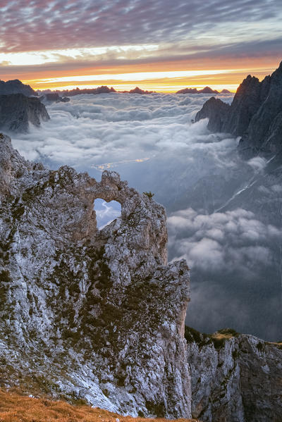 Colorful sunrise in front of the heart shaped arch of stone in the Pale of the Balconies, Pala group, Dolomites. Europe, Italy, Veneto, Agordino.
