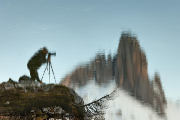 Europe, Italy, Veneto, Belluno, Cortina d Ampezzo. Silhouette of a photographer reflected in Lake Federa, Dolomites