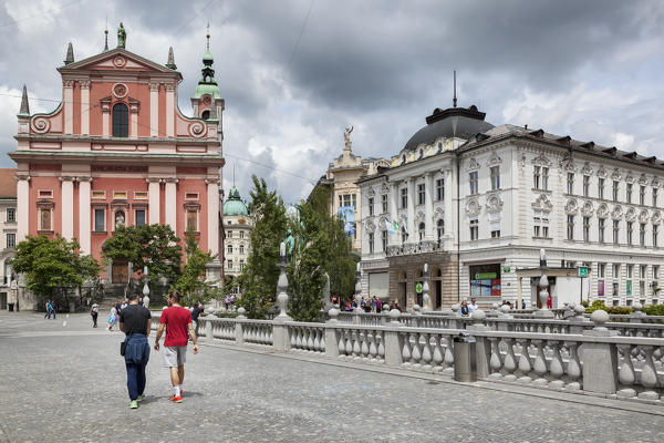 Europe, Slovenia, Ljubljana. People moving near Tromostovje and the Franciscan Church of the Annunciation