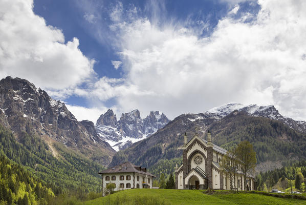 Europe, Italy, Veneto, Falcade.  The parish church and the peaks of the Focobon, Biois valley, Dolomites