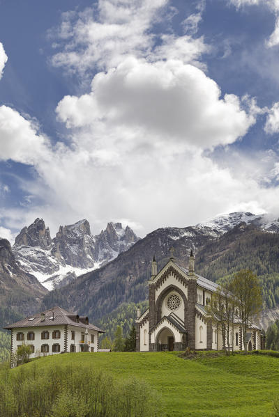 Europe, Italy, Veneto, Falcade.  The parish church and the peaks of the Focobon, Biois valley, Dolomites