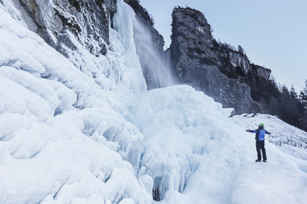 Man with opened arms in front of Gares waterfall in winter, Canale d' Agordo, Agordino, Belluno, Veneto, Italy
