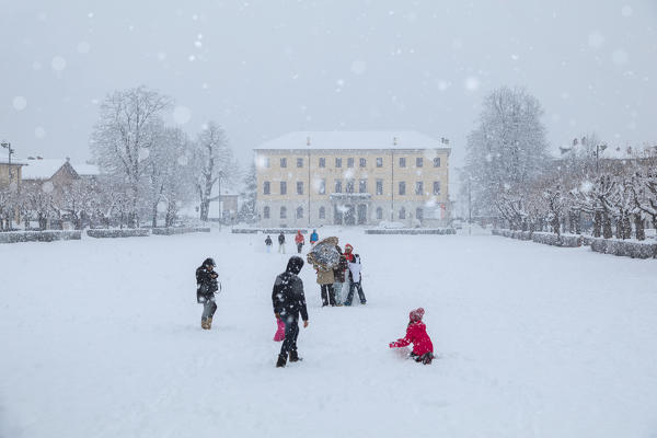 People playing under a snowfall at the main park of Agordo called Broi, Agordino, Belluno, Veneto, Italy