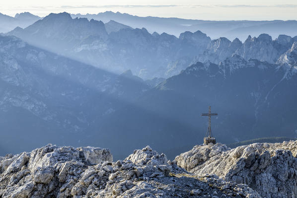 europe, Italy, Veneto, Agordino, the summit cross of mount agner, on the horizon the Monti del Sole group and Schiara group, farther away the Venetian prealps and the Venetian plain, Dolomites