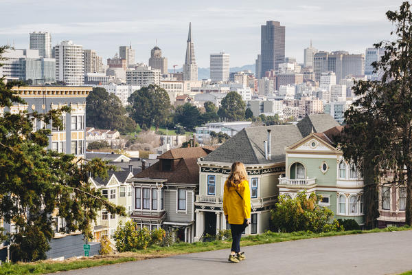 A girl walking in Alamo square, with financial district on the background, San Francisco, California, United States Of America