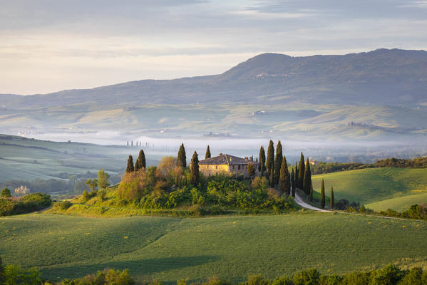 A farmhouse in the  morning between Val d'Orcia Hills. San Quirico d'Orcia, Val d'Orcia, Siena Province, Tuscany, Italy.