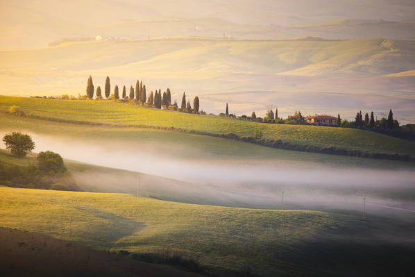 A farmhouse in the  morning between Val d'Orcia Hills. San Quirico d'Orcia, Val d'Orcia, Siena Province, Tuscany, Italy.