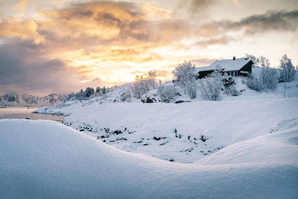 A solitary house covered with fresh snow during sunrise near Svollvaer. Lofoten Islands, Nordland, Norway.