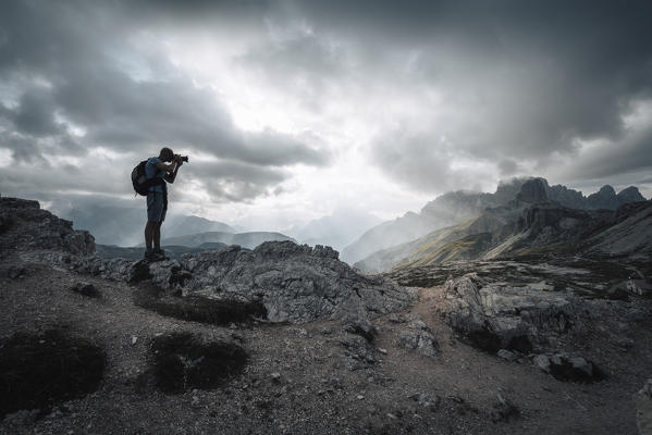 A photographer taking pictures into Dolomites. Lavaredo Three peaks, Bolzano province, South Tyrol, Italy.