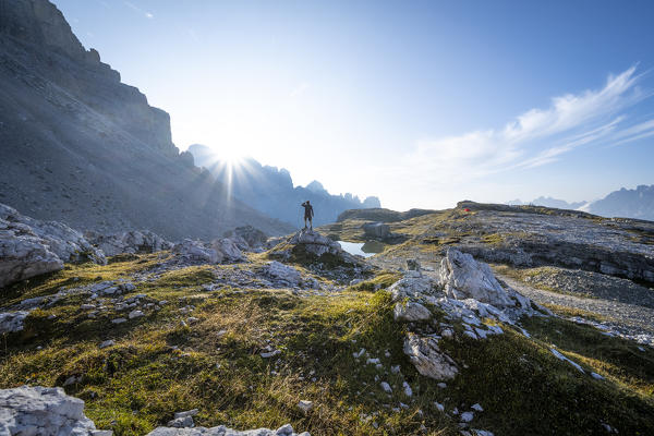 A man looking at the sun at Forcella Lavaredo, between Lavaredo three peaks and Paterno mountain. Belluno province, Veneto, Italy