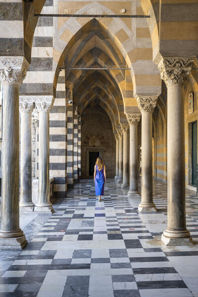 Blonde girl walking in Amalfi cathedral. Amalfi, Amalfi Coast, Sorrento province, Campania, Italy.