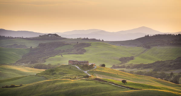 San Quirico d'Orcia, Tuscany, Italy. Podere surrounded by hills, during a warm sunrise.