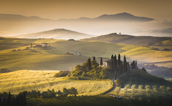 San Quirico d'Orcia, Tuscany, Italy. Podere Belvedere surrounded by hills, during a warm sunrise.