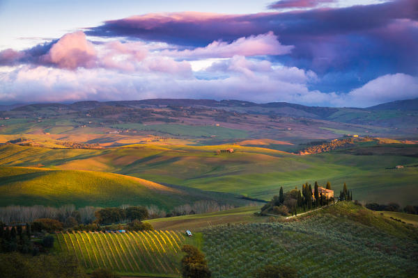 San Quirico d'Orcia, Tuscany, Italy. Sunset over the valley with some farmhouses and a very cloudy sky.