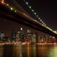 Brooklyn Bridge, uno dei ponti di Manhattan, la cui sfavillante skyline fa da sfondo nella notte di New York. Stati Uniti d'America