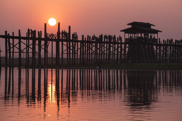 Amarapura, Mandalay region, Myanmar. Silhouetted people walking on the U Bein bridge at sunset.