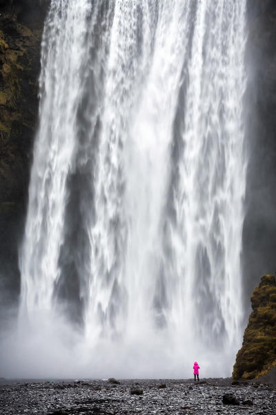 Woman staring at Skogafoss waterfall, Skogar, Gardabaer, Capital Region, Iceland, Europe